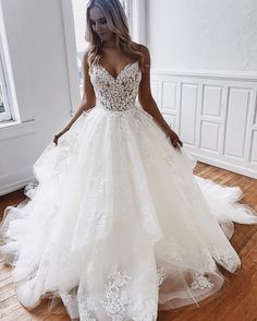 a woman in a white wedding dress standing on a wooden floor