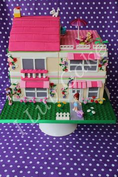 a toy house made out of legos on a purple and white polka dot background