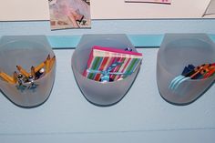 three plastic containers with pencils, scissors and other items in them on a wall