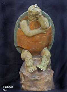 a statue of a turtle sitting on top of a rock with its head in his hands