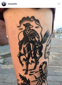 a tattoo on the leg of a man with a cowboy riding a horse and an eagle