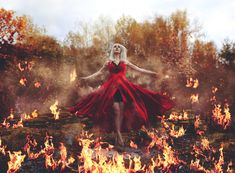 a woman in a red dress is surrounded by fire