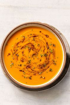 a bowl of carrot soup on a white table