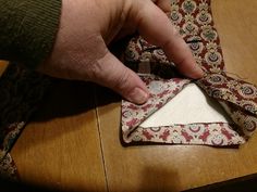 a person is tying a tie on top of a piece of cloth that has been sewn together