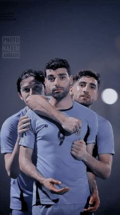 three men hugging each other in front of a dark background