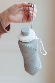 a person holding a water bottle with a pair of scissors attached to the top of it