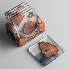 two glass coasters with wood slices on them sitting on a gray surface next to each other