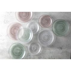 six glass plates sitting on top of a cement floor next to each other in different shapes and sizes