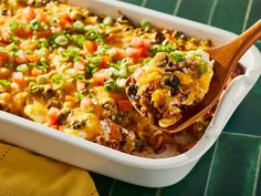 a casserole dish with beans, peas and other toppings on a wooden spoon