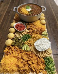 a platter filled with chips, dips and other food on top of a wooden table