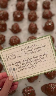 a person holding up a card with chocolate truffles in the background and writing on it