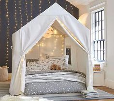 a bed with a white canopy over it in a room filled with furniture and lights