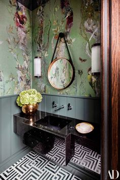 the bathroom is decorated in green and gold with flowers on the wall, mirror above the sink