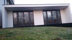 a house that has some glass doors on the side of it and grass in front of it