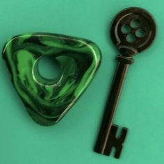 a green and black key laying on top of a blue table next to a bottle opener