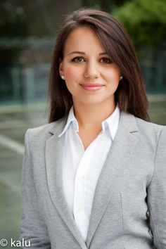 a woman in a gray suit and white shirt smiling at the camera with her hands on her hips