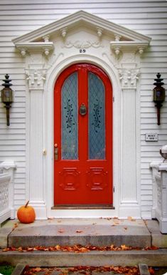 a red front door with two pumpkins on the steps