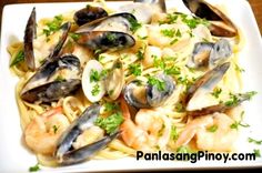 pasta with shrimp, mussels and parmesan cheese sauce on a white plate