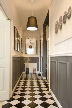 a hallway with black and white checkered flooring next to a wall mounted light