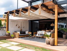 an outdoor living area with wooden furniture and white drapes on the roof, surrounded by greenery