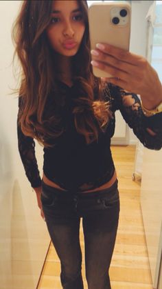 a young woman taking a selfie in front of a mirror with her cell phone