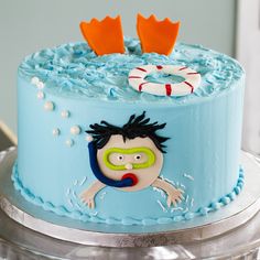 a blue cake decorated with an image of a boy swimming in the water and two life rings on top