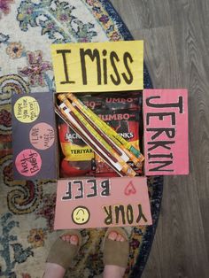 someones feet in front of a box with candy and books on it that says i miss