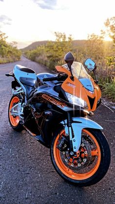 an orange and black motorcycle parked on the side of a road