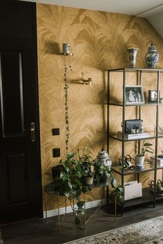 a living room filled with lots of plants next to a wall covered in gold leaves