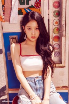 a young woman sitting on top of a red chair next to a vending machine