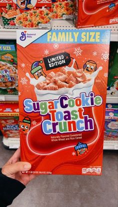 a person holding up a box of sugar cookie toast crunch in front of some shelves