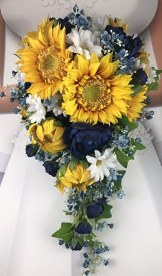 a bridal bouquet with sunflowers and blue hydrangeas on the bride's dress