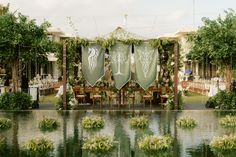 an outdoor dining area with tables and chairs covered in green cloths, surrounded by greenery