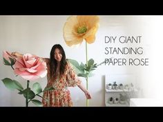 a woman standing in front of a flower with the words diy giant standing paper rose