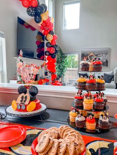 a mickey mouse themed birthday party with cupcakes, cookies and desserts on the table