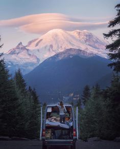 a van parked on the side of a road in front of a mountain covered in snow