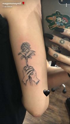 a person with a tattoo on their arm holding a flower in one hand and the other