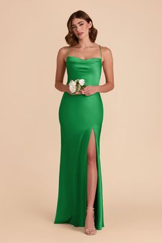 a woman wearing a green dress with a slited skirt and flower in her hand