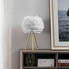 a book shelf with a lamp on top of it next to a painting and bookshelf