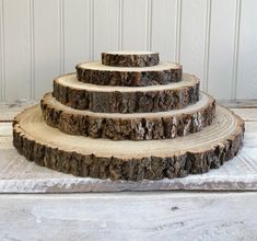 three tiered wooden cake stand made out of tree slices on a white wood floor