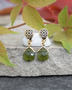 These pretty emerald green crystal drop and stud earrings have a gorgeous celtic knot design. Suspended from the ear post are gorgeous emerald green Swarovski crystal briolettes. The facetted crystals really catch the light beautifully. The earrings are made from top quality Tierracast findings.  All components are lead and nickel free.   Presented in a black gift box with gold embossed logo.  Also available with champagne briolettes. Shipped in a postal box, plastic free . Ships from United Kin Elegant Green Polished Earrings, Celtic Beaded Earrings, Celtic Earrings Studs, Outlander Jewelry, Irish Earrings, Nickel-free Green Drop Crystal Earrings, Emerald Green Crystal, Celtic Knot Earrings, Celtic Knot Designs