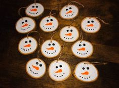 twelve snowman cookies are arranged on a wooden table with twine and string around them