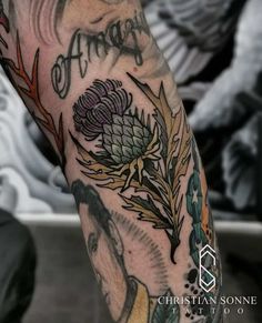 a man's arm with tattoos on it and flowers in the middle of his arm