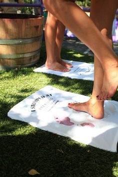 two people standing on towels with their bare feet in the grass next to a barrel