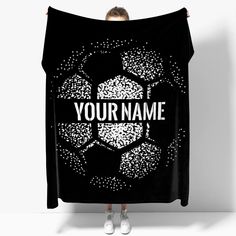 a woman holding up a black blanket with the words your name on it and a soccer ball