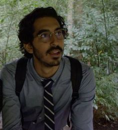 a man wearing glasses and a tie in the woods