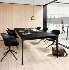 a black table and chairs in a room with wood flooring next to a large window