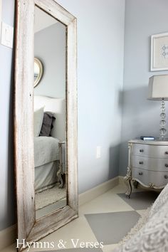 a bedroom with a large mirror on the wall next to a white dresser and bed