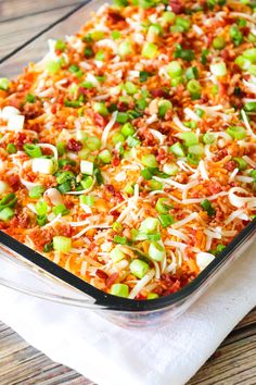 a casserole dish with meat, cheese and green onions in it on a wooden table