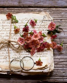 an old book with flowers on it and two wedding rings sitting next to each other